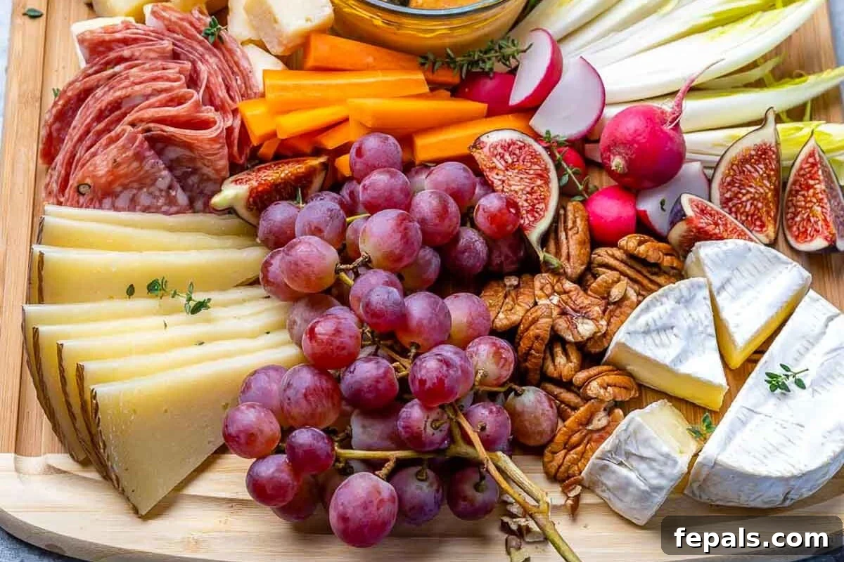 A Symphony of Flavors Fruit and Cheese 3 An overhead view of a well-stocked cheese and fruit platter, featuring various cheeses, fresh berries, grapes, crackers, and nuts on a rustic cutting board.