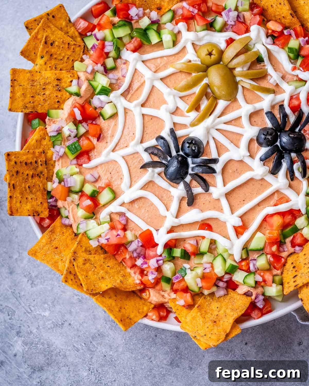 Top view of the decorated taco dip showing the veggie border and tortilla chips around the dish.