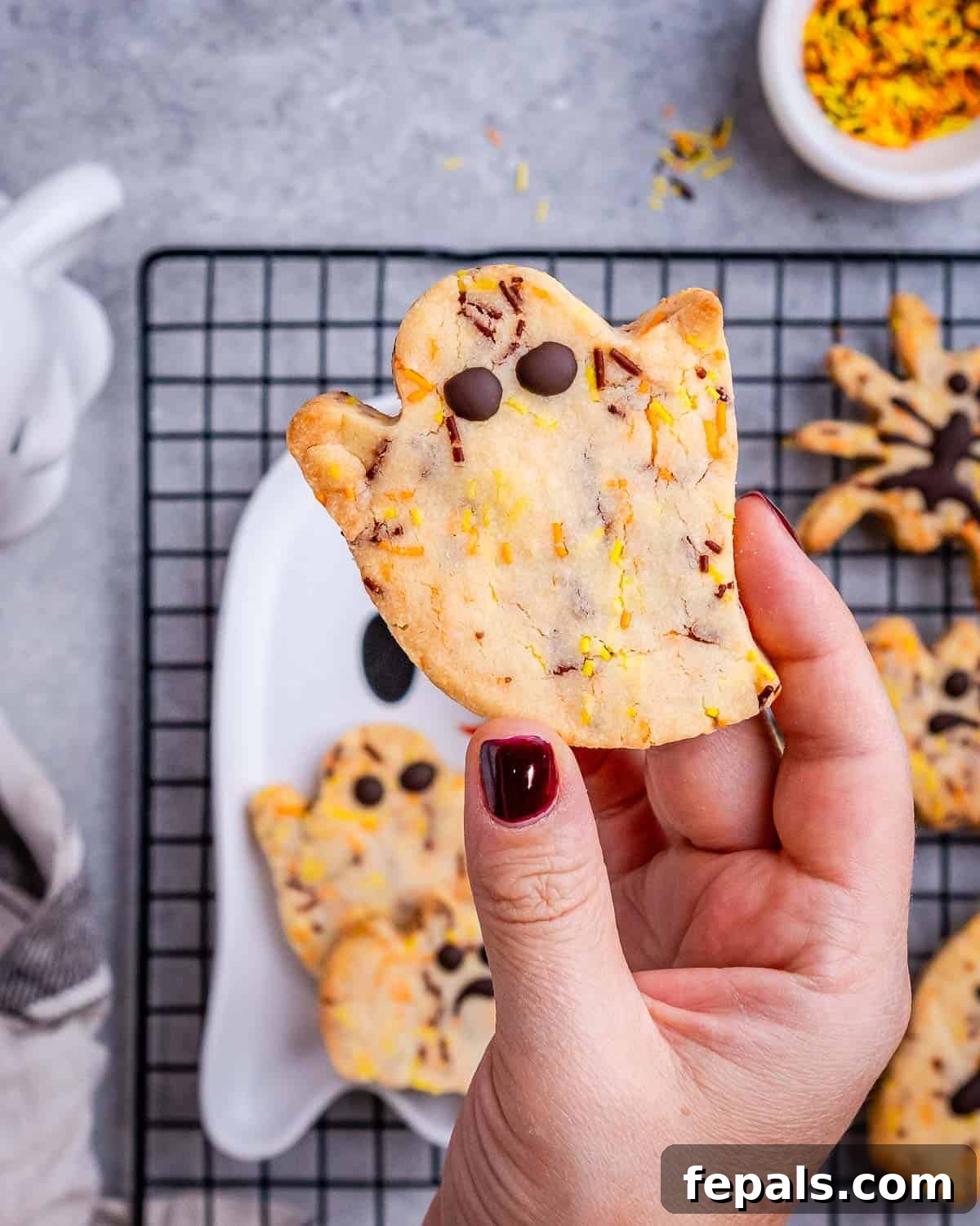 Spooktacularly Easy Halloween Cookies Kids Will Love 6 A hand holding a freshly baked and decorated Halloween ghost cookie.