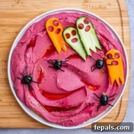 a bowl with purple hummus and spiders made out of black olives.