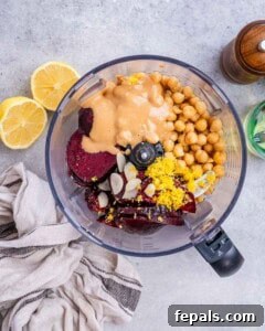 ingredients for beet hummus are added into a blender.