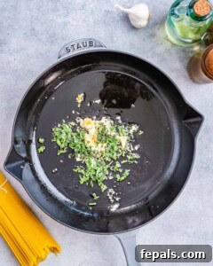Minced garlic and chopped fresh sage leaves sizzling in olive oil in a skillet.