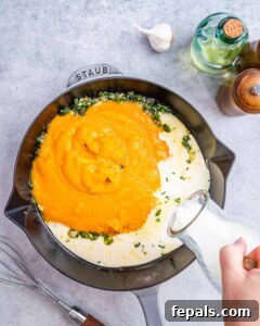 Pumpkin puree and milk being whisked together in a skillet to form a smooth sauce base.