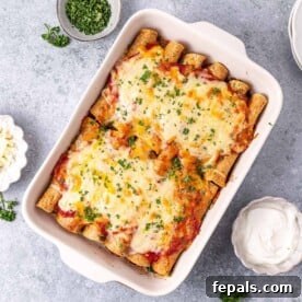 A top-down view of bubbling beef enchiladas baked to perfection in a white dish, generously topped with golden-brown melted cheese and a rich red sauce.