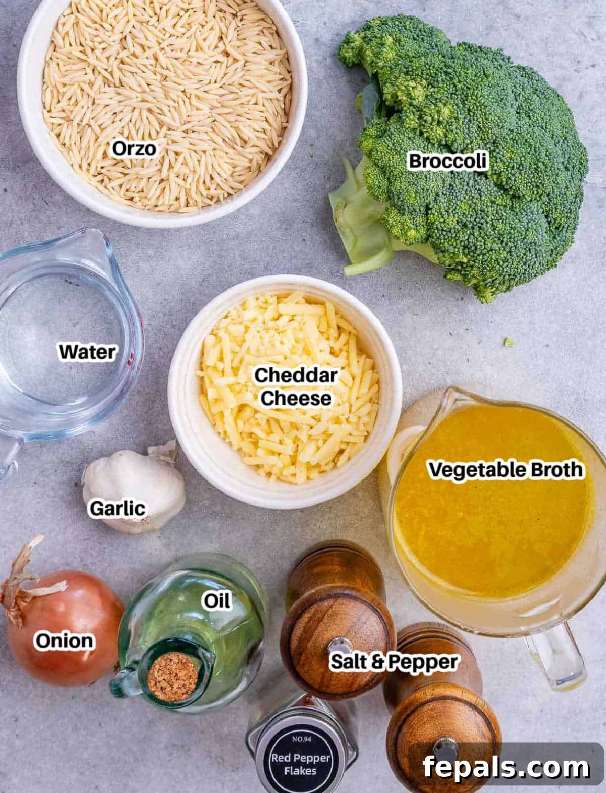 A collection of fresh ingredients laid out, including broccoli, cheese, onion, garlic, orzo, and spices, ready for cooking.