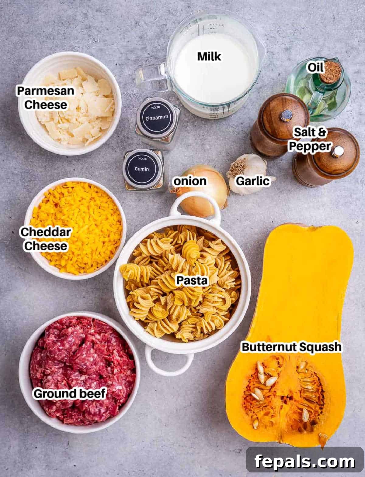 Savory Butternut Squash & Beef Ragu Pasta 3 A rustic wooden board displaying fresh ingredients for butternut squash pasta: cubed squash, olive oil, spices, ground beef, onion, garlic, milk, and cheeses.