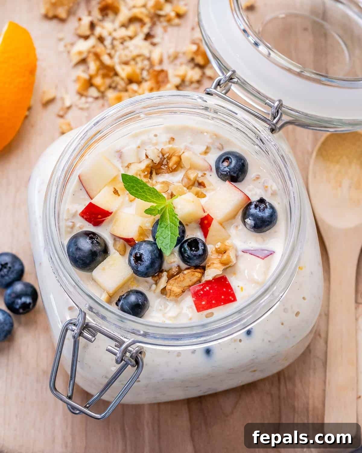 A jar filled with Princess Diana's overnight oats, topped with chopped apples and fresh blueberries, ready to be enjoyed as a healthy breakfast.