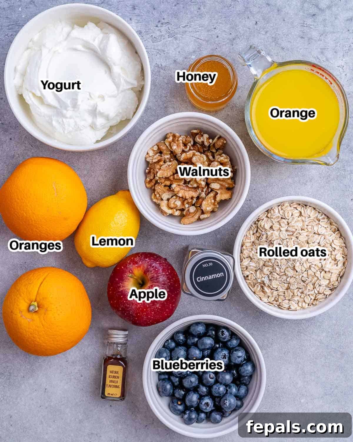 A selection of fresh ingredients including rolled oats, oranges, apples, lemon, Greek yogurt, blueberries, and walnuts, laid out for Princess Diana's overnight oats recipe.