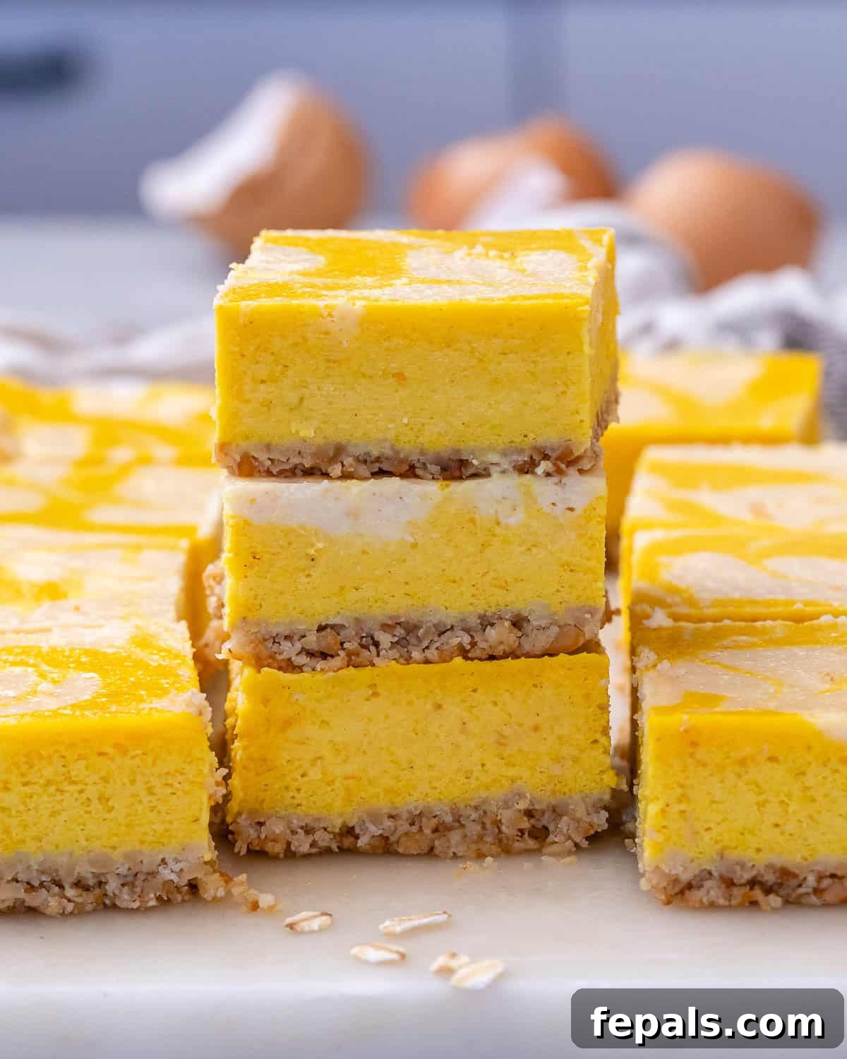 Decadent Pumpkin Spice Cheesecake Bars 2 Tall stack of pumpkin cheesecake bars arranged neatly to display the layers and vibrant pumpkin color.