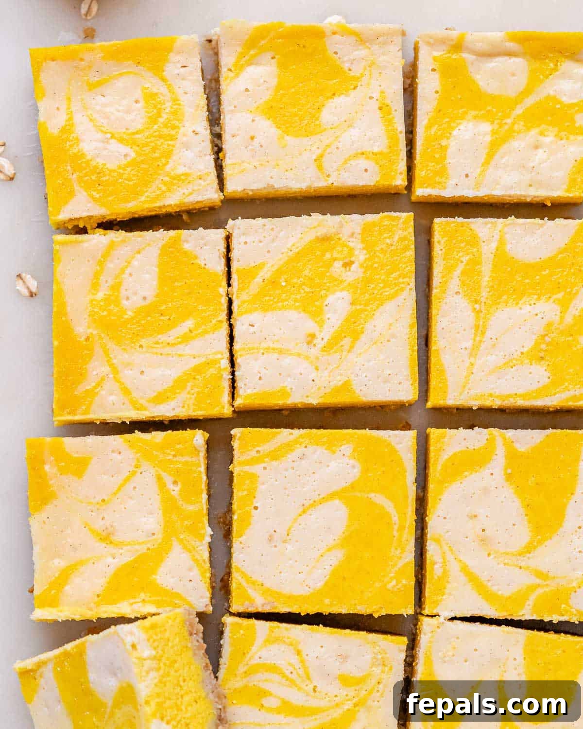 Decadent Pumpkin Spice Cheesecake Bars 7 Pumpkin cheesecake bars sliced evenly into neat squares on parchment paper after cooling.