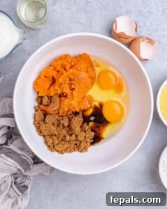 Golden Gluten Free Sweet Potato Cornbread 11 A mixing bowl filled with mashed sweet potato, brown sugar, eggs, and oil ready to be whisked together for the cornbread batter.