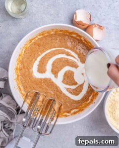 Golden Gluten Free Sweet Potato Cornbread 12 Buttermilk being poured into the sweet potato mixture while it’s whisked to create a smooth, creamy batter.
