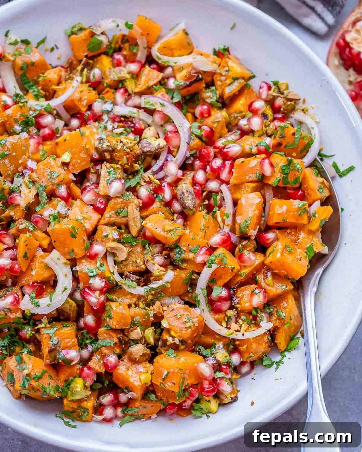 Flavorful Roasted Sweet Potato Salad Gluten Free 2 Overhead view of vibrant sweet potato salad with herbs, pistachios, red onion, and pomegranate seeds in a serving bowl.