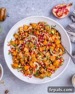 Overhead view of prepared sweet potato salad ready to serve, highlighting the orange, green, and red color contrast.