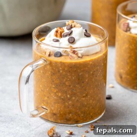 A side view of a glass cup filled with rich pumpkin overnight oats, layered and ready to enjoy as a nutritious make-ahead breakfast.