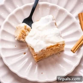 Cinnamon Swirl Dream Cake 10 A delightful portion of cinnamon roll cake on a plate, with a fork gently resting beside it, inviting you to take a bite.