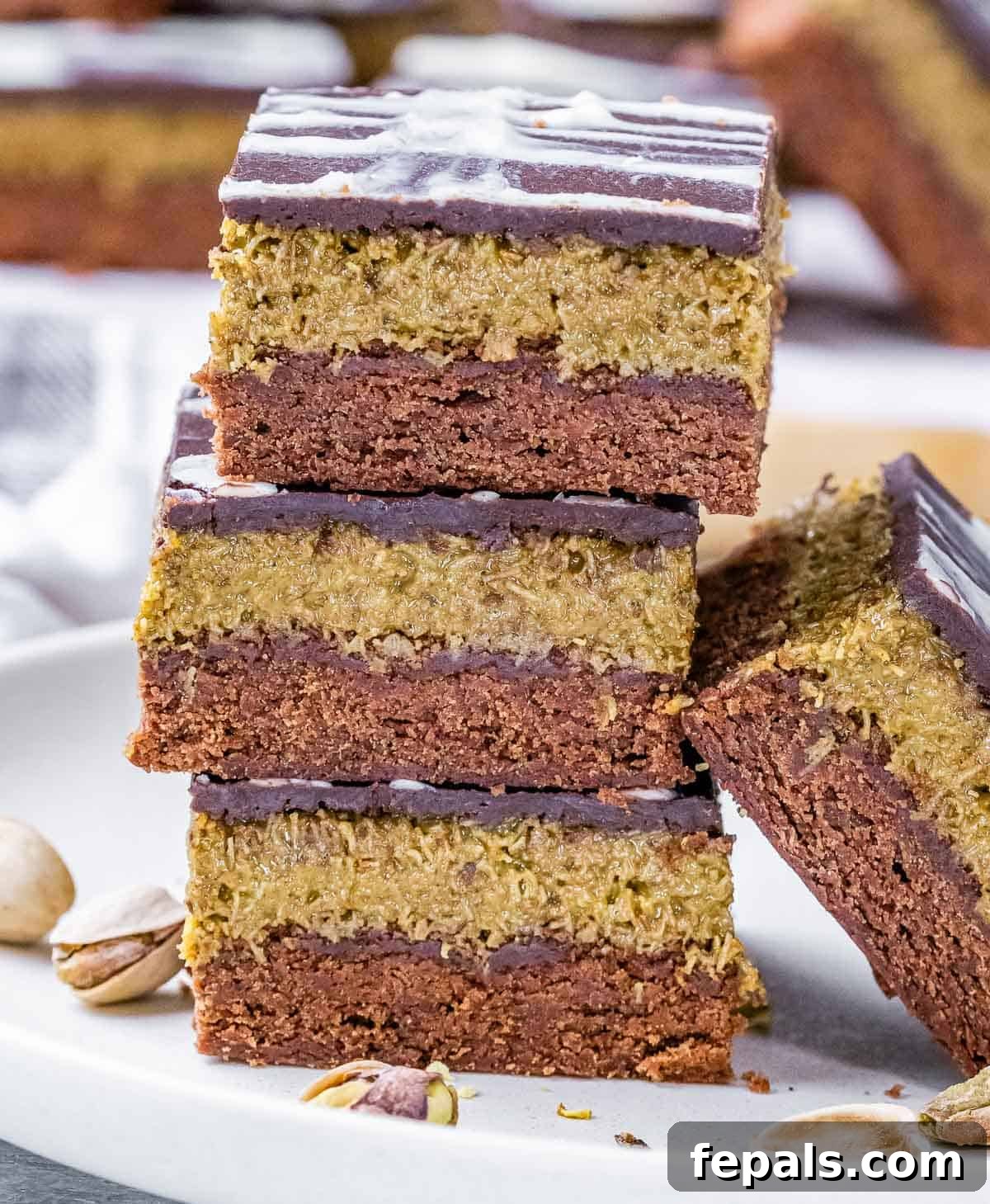 A stack of Dubai brownies with pistachios and ganache topping.