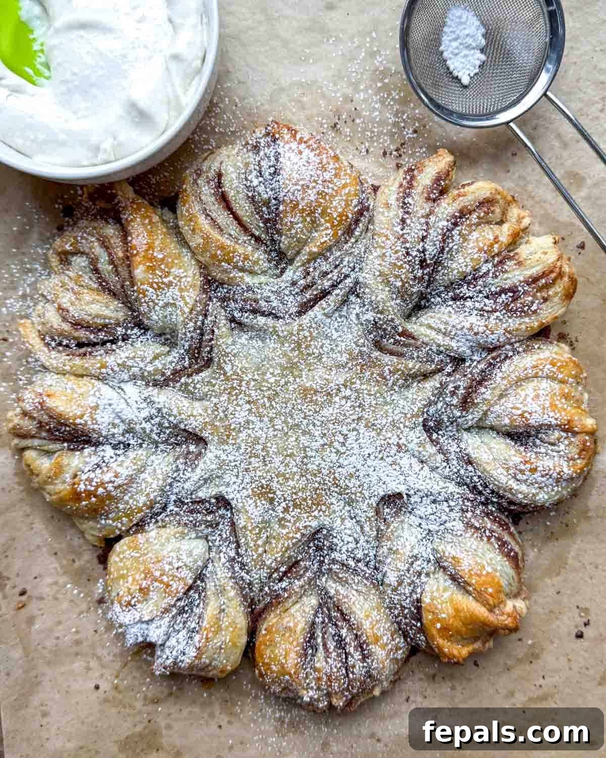 A beautifully baked cinnamon roll puff pastry snowflake, dusted with powdered sugar and ready to be served.