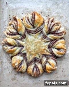 The freshly baked puff pastry snowflake resting on a sheet pan after being removed from the oven.