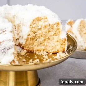 A beautifully sliced Coconut Bundt Cake, showcasing its moist interior and snowy coconut topping.