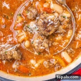 A ladle expertly scooping a portion of rich meatball and bean soup, highlighting the tender meatballs and hearty beans.
