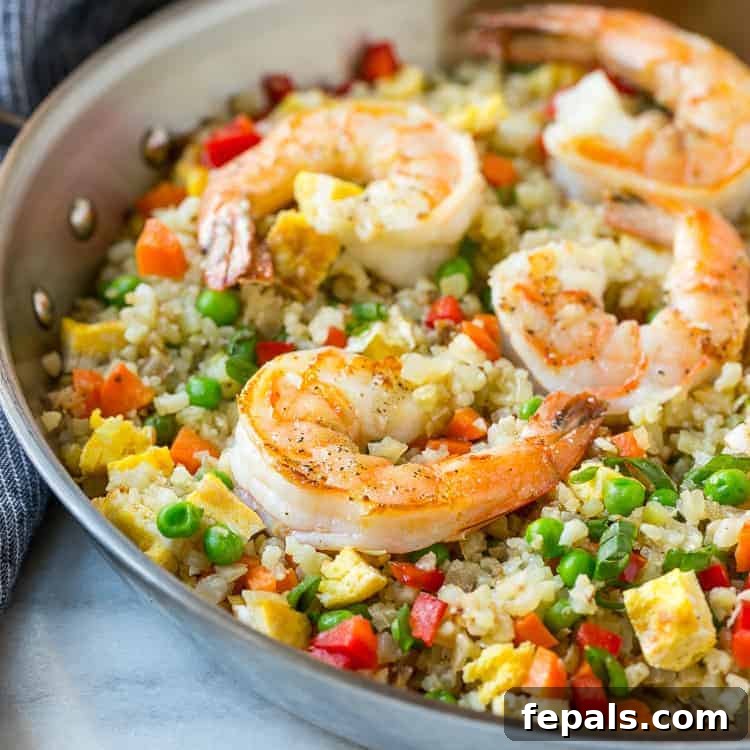 Shrimp Fried Rice Recipe: A Wholesome & Quick Meal Close-up of healthy cauliflower fried rice with shrimp, peas, and carrots in a skillet.