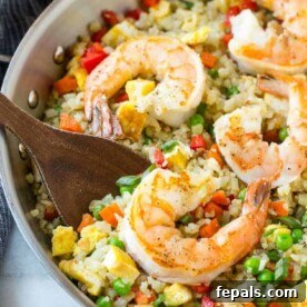 Shrimp Cauliflower Fried Rice in skillet with wooden spoon