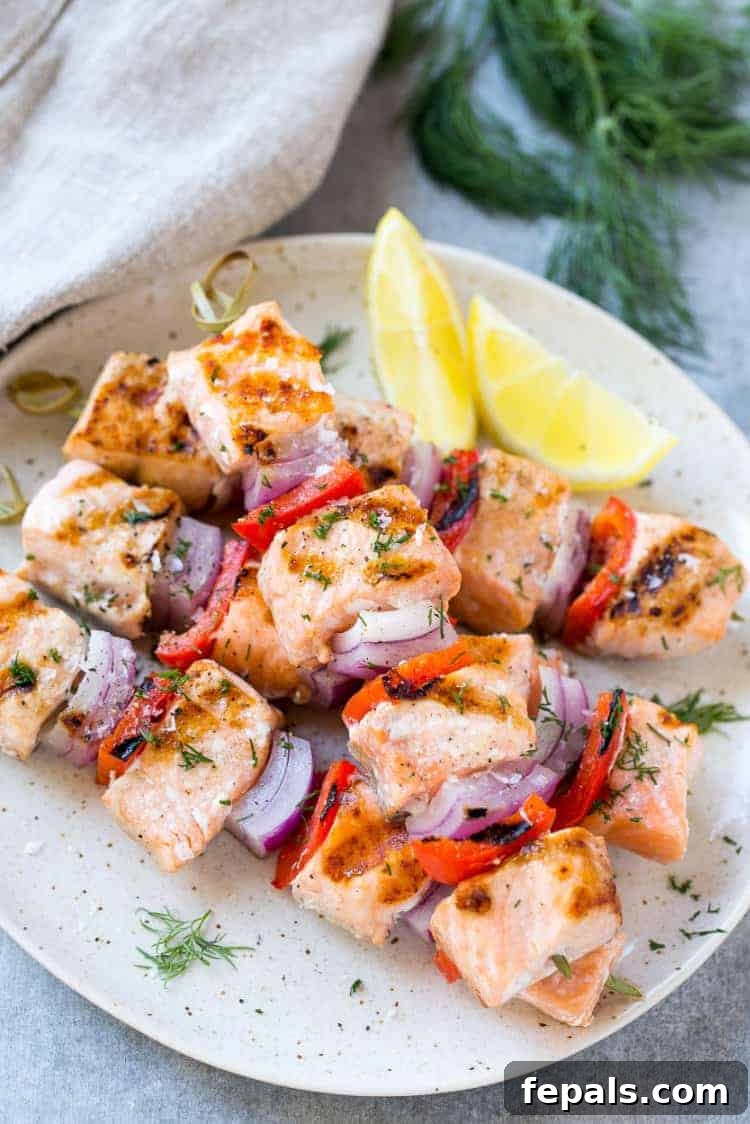 Close up of grilled salmon on a plate and veggies on skewers, showing the delicious char marks and vibrant colors
