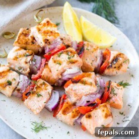 Lemon Dill Salmon Skewers on white plate with lemon and vegetables