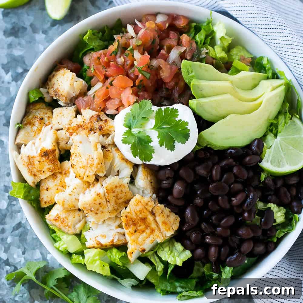 Tasty Taco Salad Bowl Recipe with Fish A beautifully presented taco salad in a bowl, featuring flaky fish, creamy avocado, hearty black beans, vibrant salsa, and a generous dollop of sour cream, ready to be enjoyed.