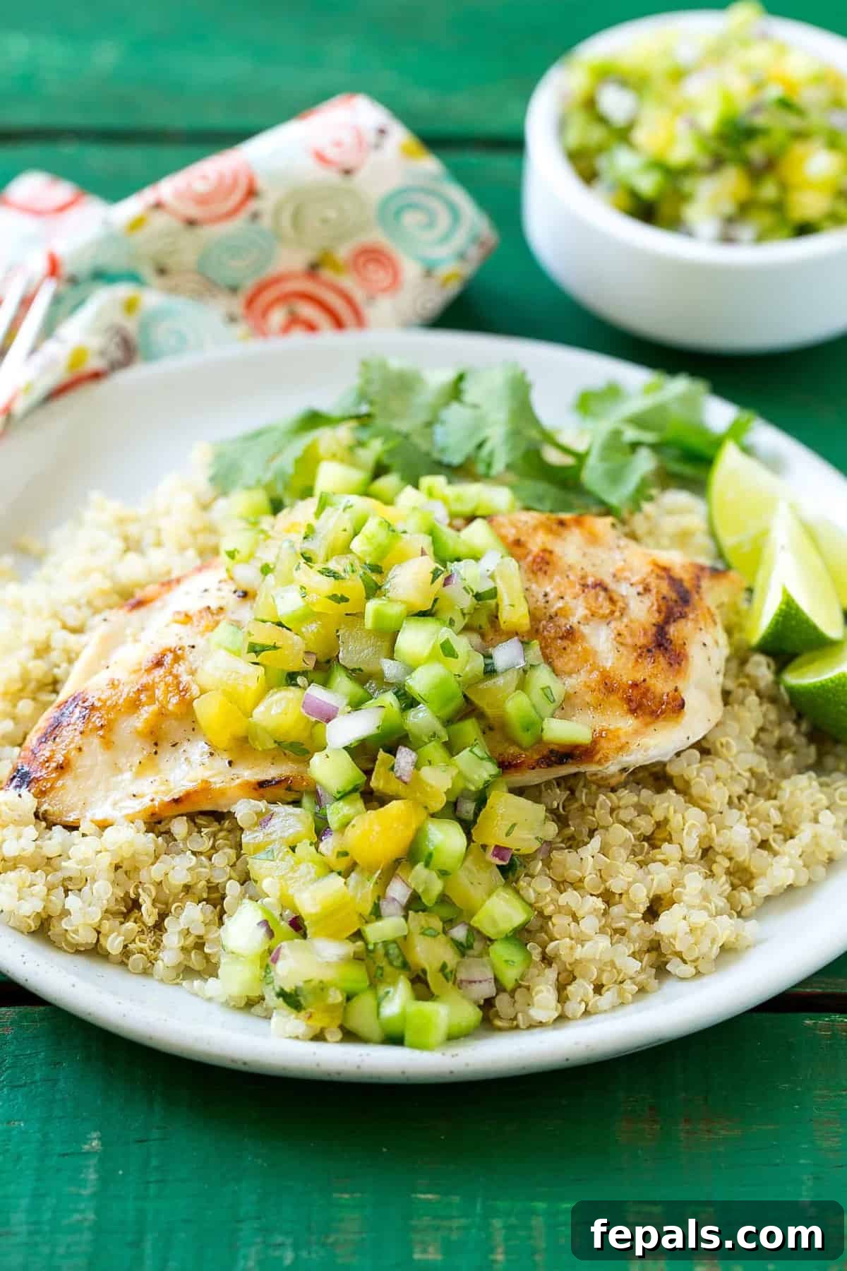 Mediterranean Grilled Chicken Quinoa 4 A completed dish of grilled chicken, quinoa, and pineapple salsa on a white plate, garnished with fresh cilantro.