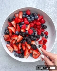 hand mixing the berry salad using a spoon.