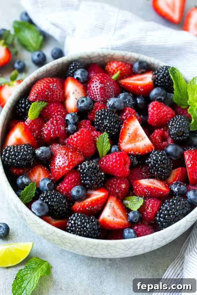 side shot of Mixed Berry Fruit Salad in a white bowl with lime wedge for garnish