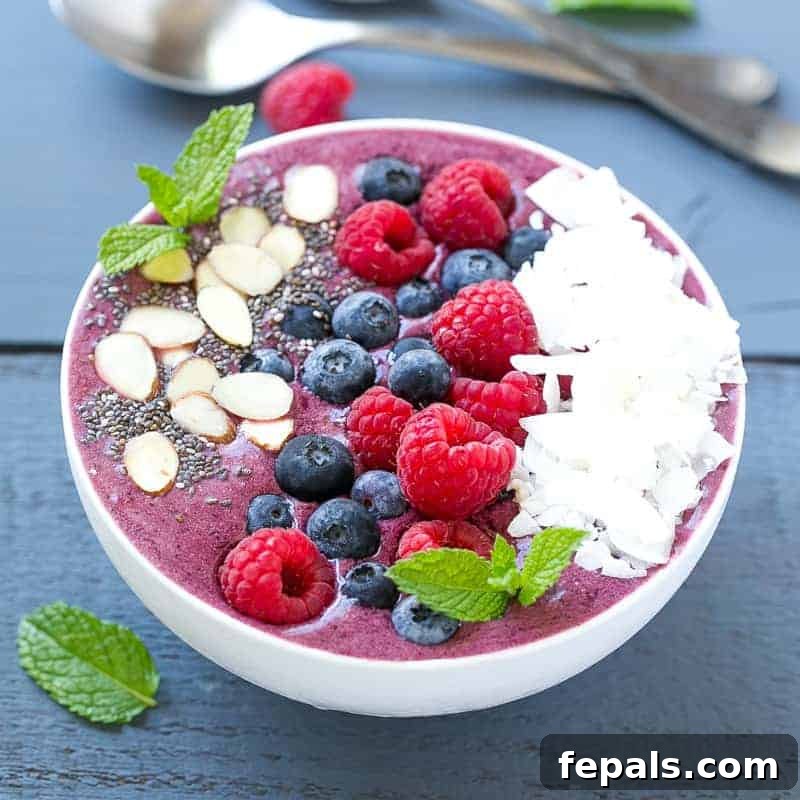 Berry Burst Bowl 2 A beautifully arranged berry smoothie bowl, topped generously with fresh, colorful berries, crunchy sliced almonds, and delicate coconut flakes, inviting a wholesome start to the day.