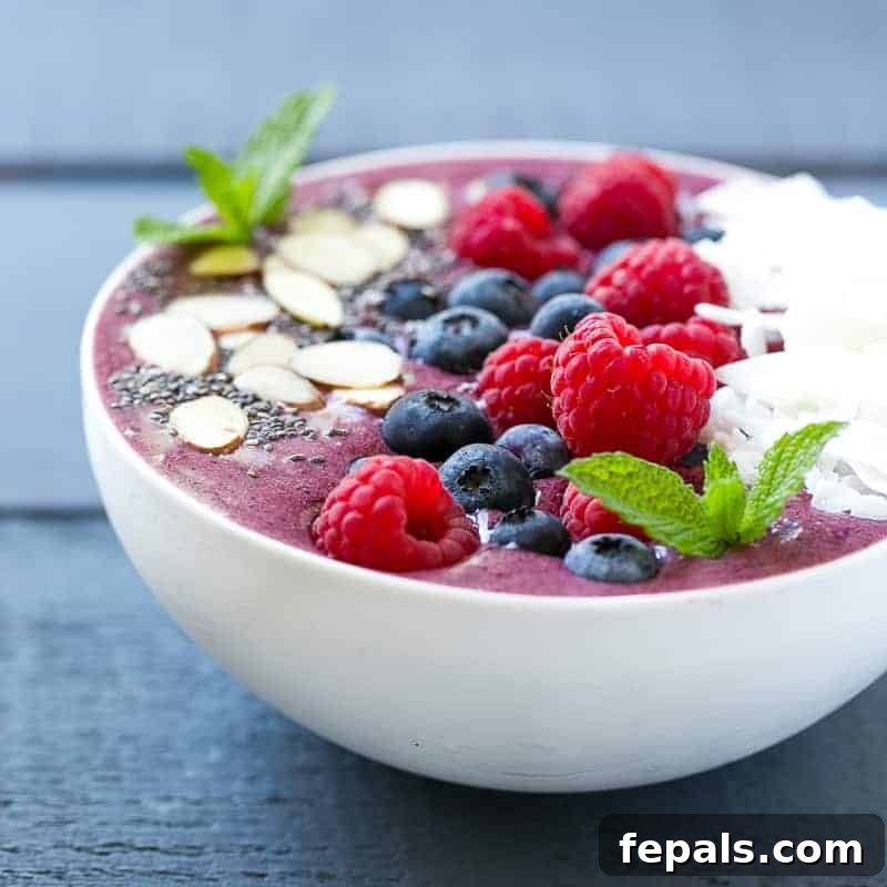 Berry Burst Bowl 3 A captivating side shot of a rich berry smoothie bowl, elegantly adorned with an assortment of fresh berries and delicately shaved coconut flakes, showcasing its enticing texture.