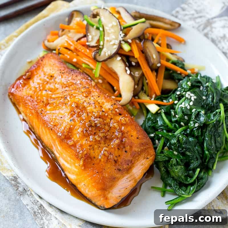Top view of a beautifully pan-seared honey glazed salmon fillet served with a vibrant side of vegetables on a white plate, ready for a quick weeknight dinner.
