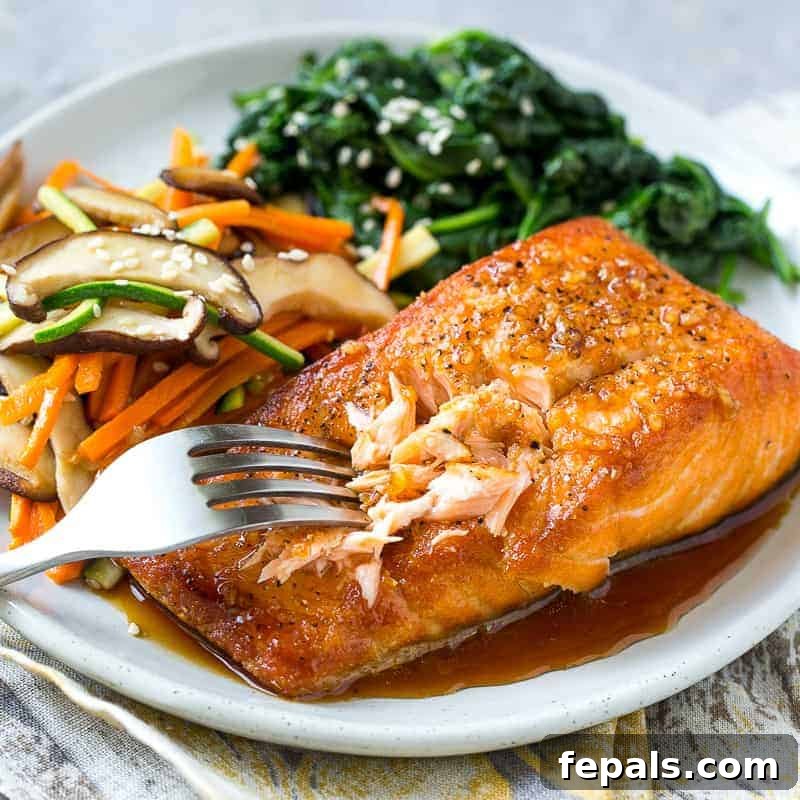 Close-up of a fork gently flaking a piece of perfectly seared salmon on a white plate, highlighting its moist and tender texture, with a side of sautéed vegetables and spinach.