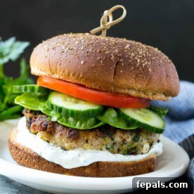 One perfectly cooked turkey feta burger with fresh lettuce, cucumber, tomato, and a side of tzatziki sauce.