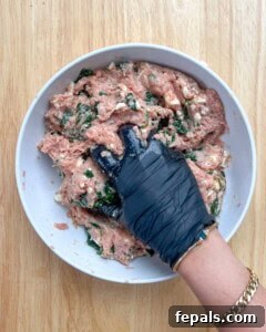 Hand mixing all the burger ingredients in a bowl.