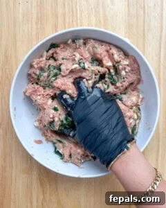 Hand mixing all the burger ingredients in a bowl.
