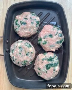 4 burger patties are placed on a pan before cooking.