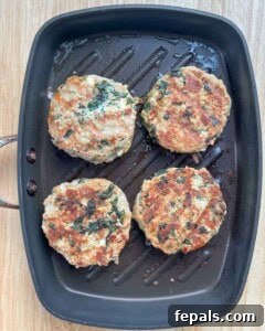 4 cooked burger patties on a pan.