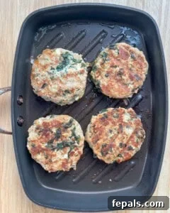 4 cooked burger patties on a pan.