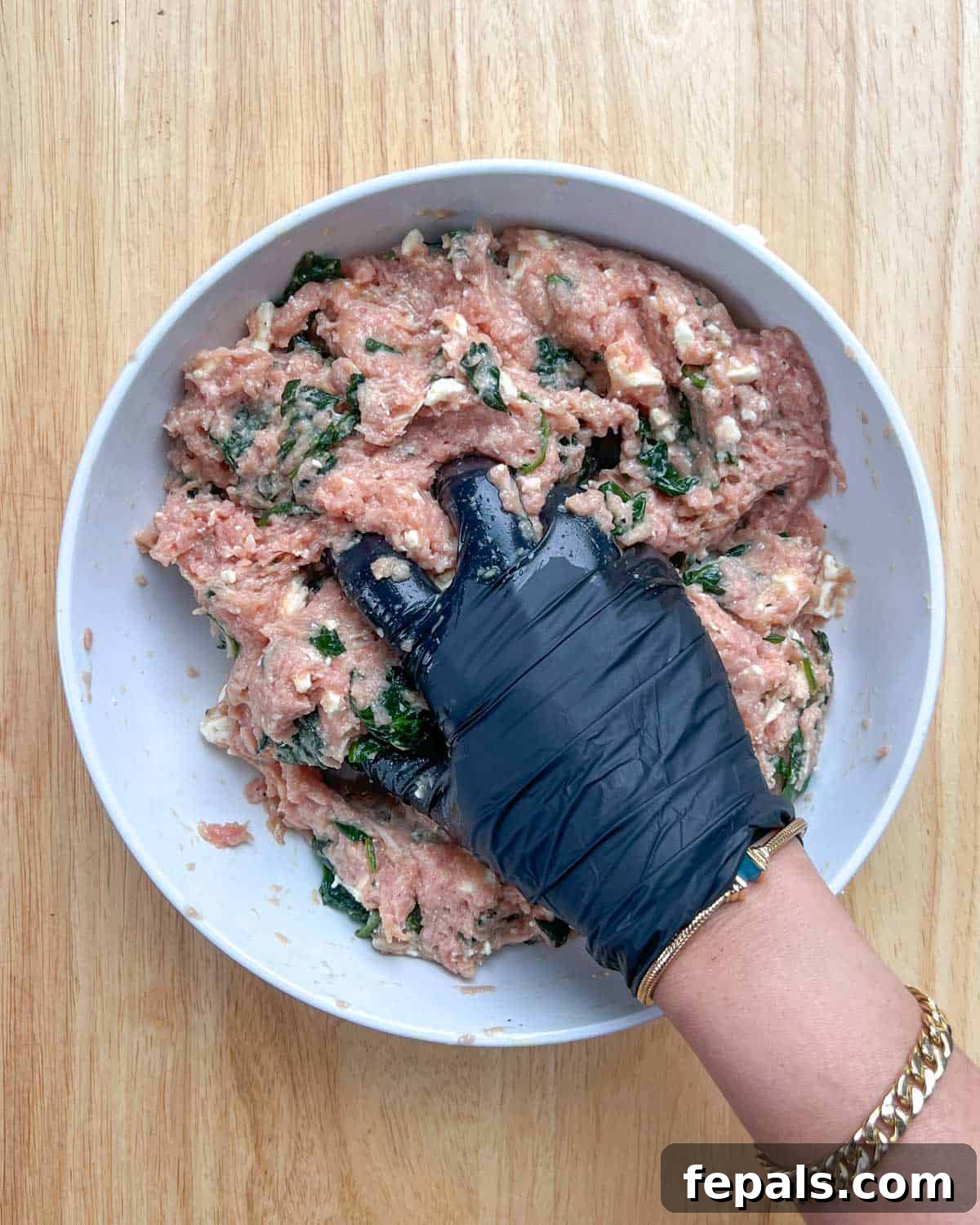 Gourmet Spinach and Feta Turkey Burgers 5 A hand mixing all the turkey burger ingredients thoroughly in a bowl.