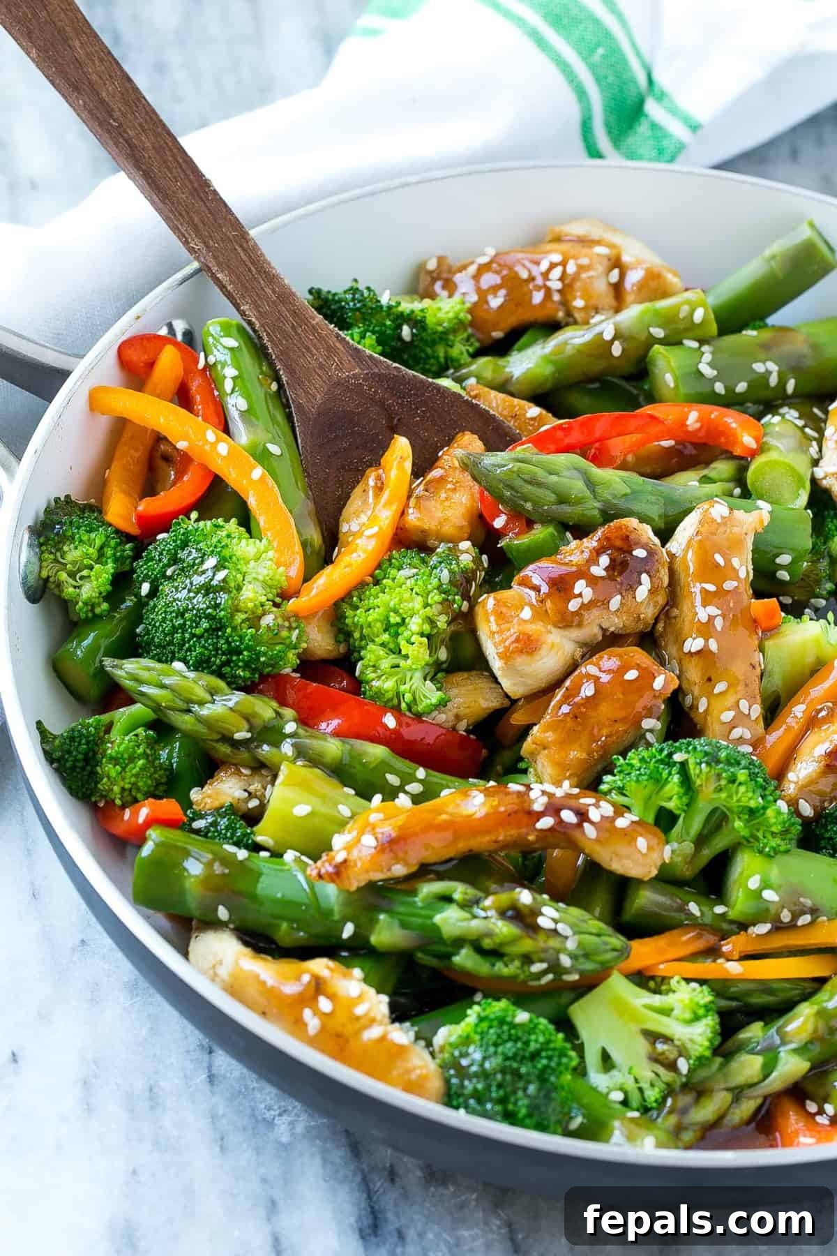 teriyaki chicken stir fry in skillet with wooden spoon