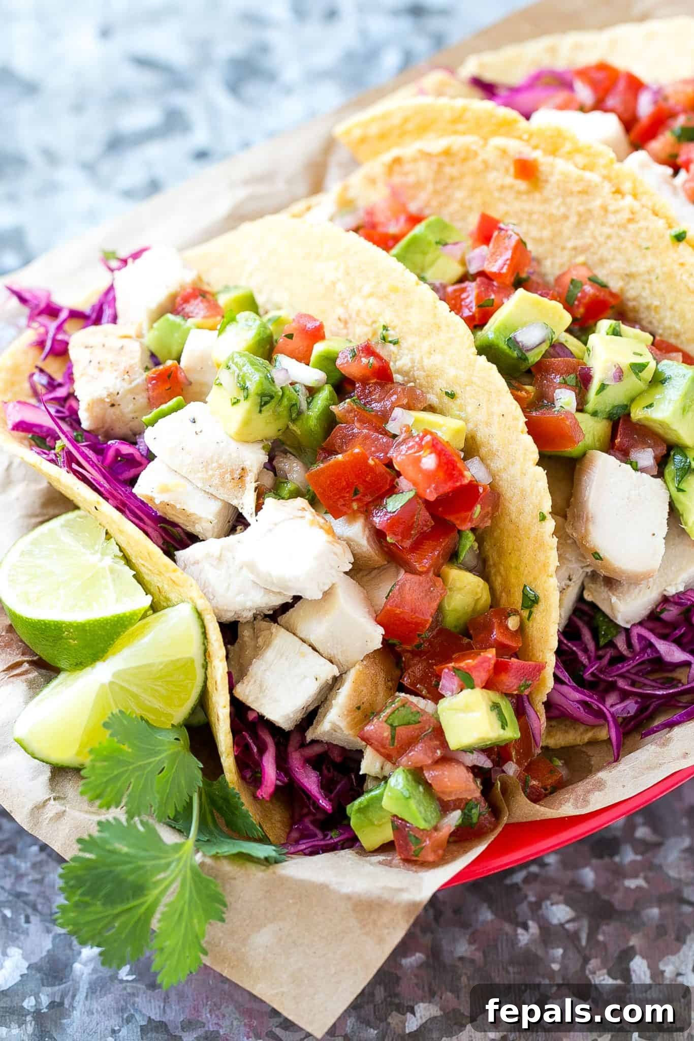 two chicken tacos in a basket with lime wedges and cilantro