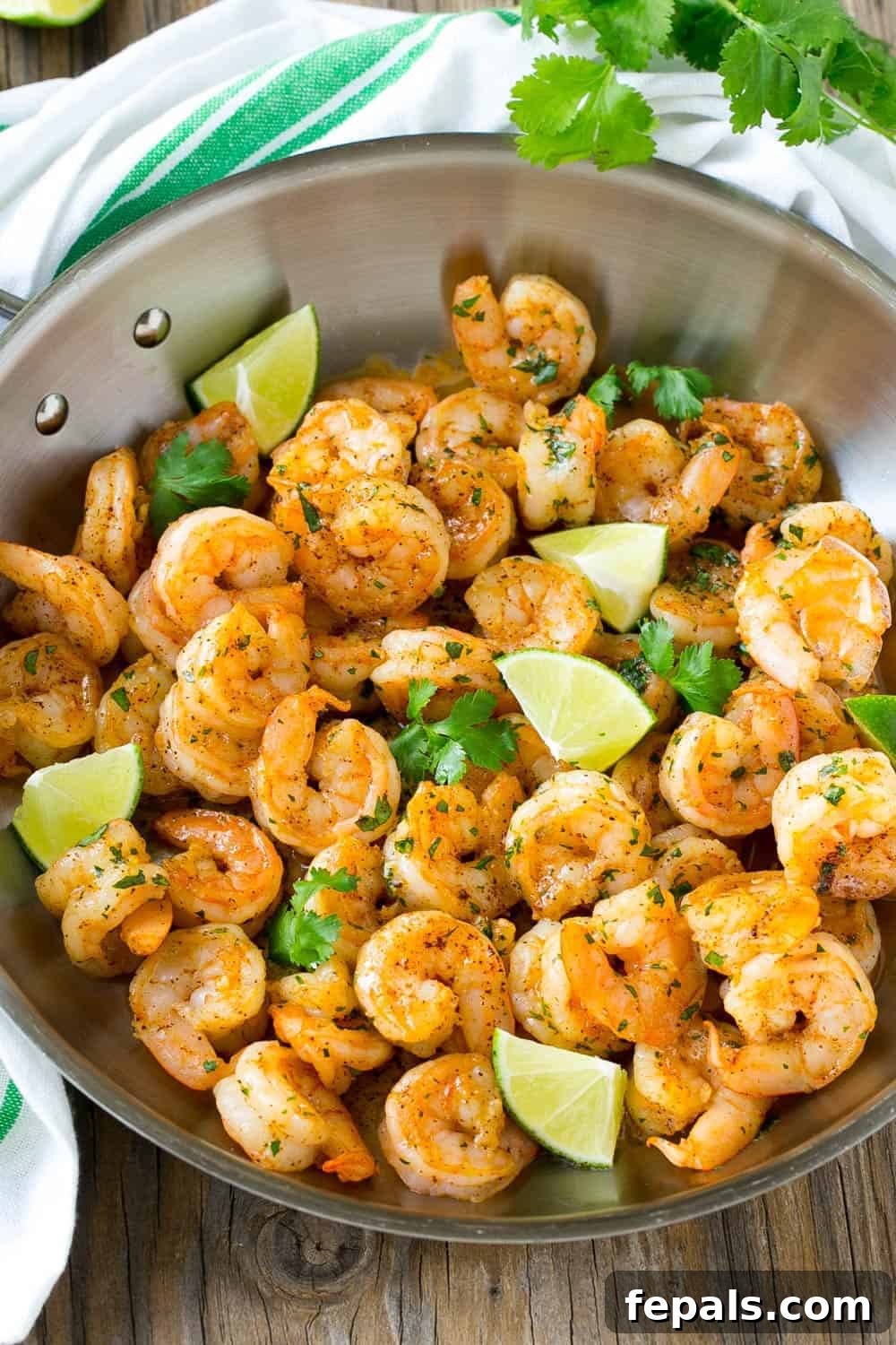Close-up of cooked cilantro lime shrimp with lime wedges and fresh cilantro