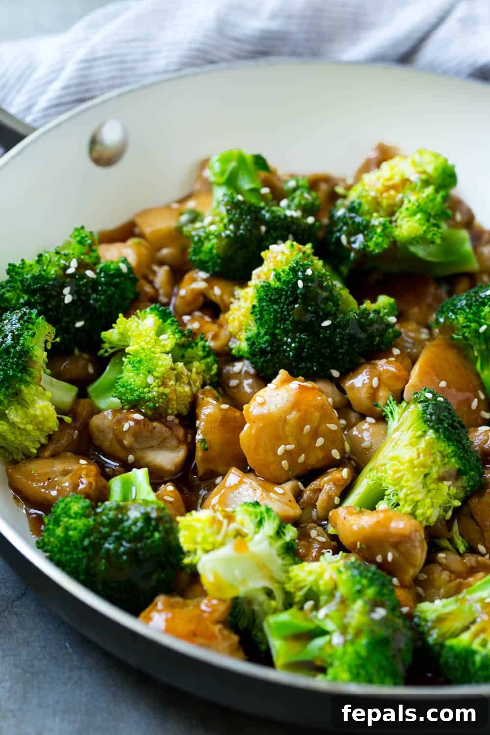 Healthy Chicken and Broccoli Stir-Fry with Garlic and Sesame Seeds A bowl of freshly cooked broccoli and chicken stir-fry, generously coated in a rich, glossy sauce and topped with toasted sesame seeds, emphasizing its healthy and delicious appeal.