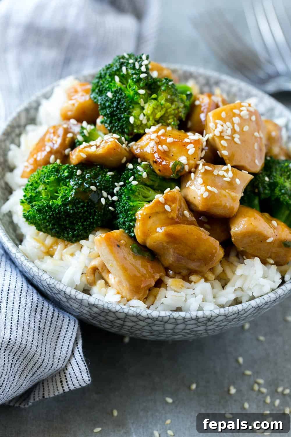 Healthy Chicken and Broccoli Stir-Fry with Rice A vibrant bowl of healthy chicken and broccoli stir-fry, served over a bed of white rice and garnished with sesame seeds, presenting a complete and appealing meal.