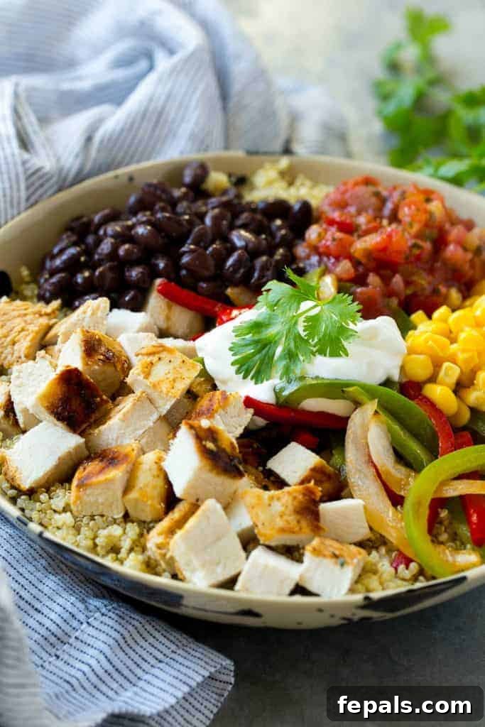 Side view of a healthy chicken and quinoa meal prep bowl with fresh toppings